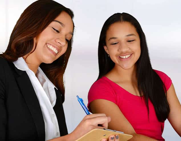 teen girl looks on as therapist writes something