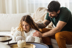 father comforting teen daughter and talking to her about trying out teen relationship counseling