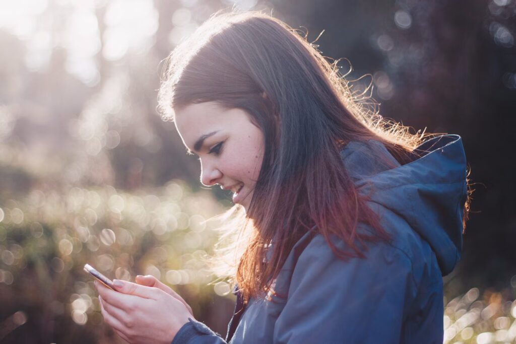 Smiling teen girl absorbed in her phone